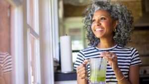 Home 39 Woman drinking herbal tea to alleviate perimenopause bloating and weighing options like hrt during perimenopause.